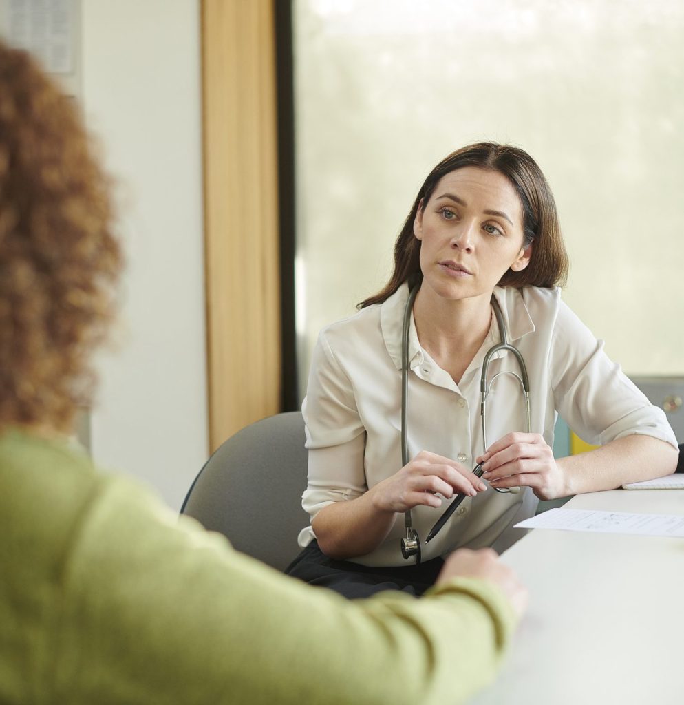 A GP listening to a patient during a consultation